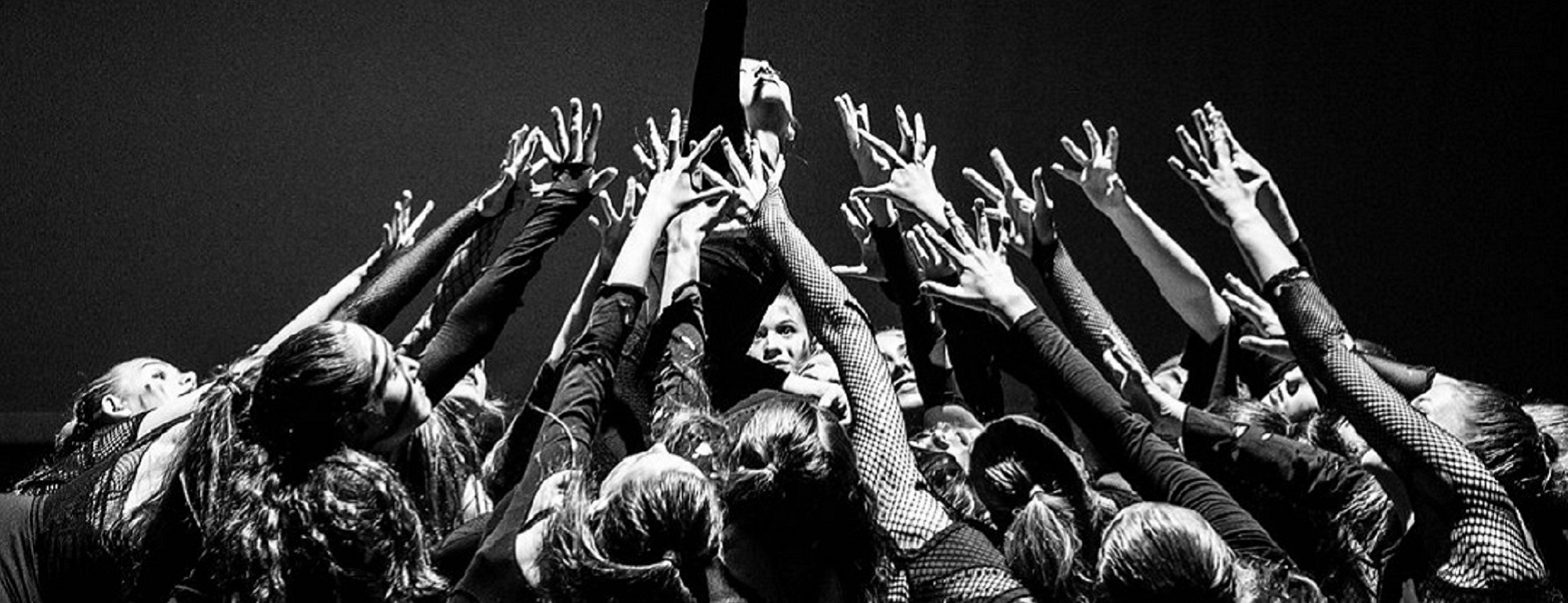 Black and white photo of dancers in a group with their hands in the air