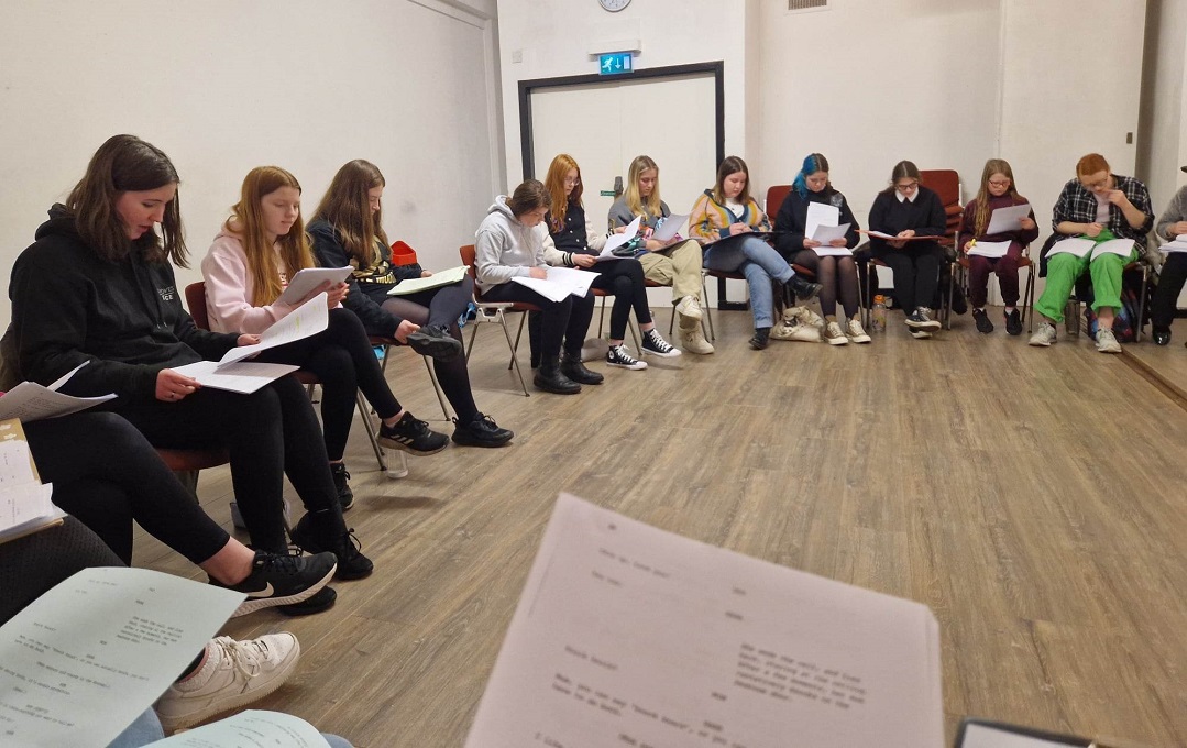 Young people sitting in a circle reading scripts
