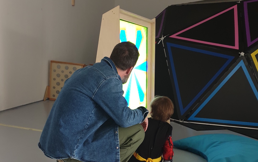 A father and child looking at a colourful lightbox
