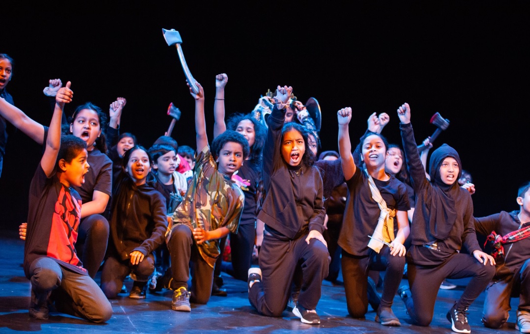 A group of children in a play with their fists in the air and shouting