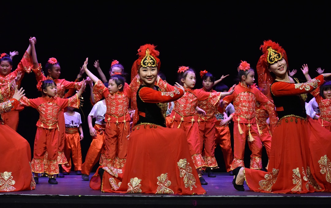 Traditional Chinese dancers dressed in red performing on a stage