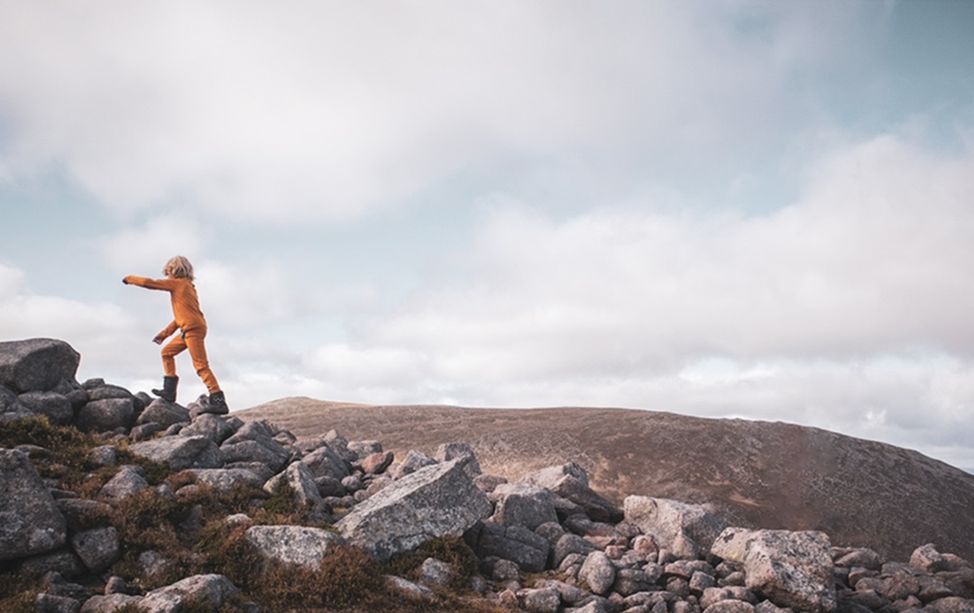 A picture of a child wearing a yellow jacket and walking up a hill