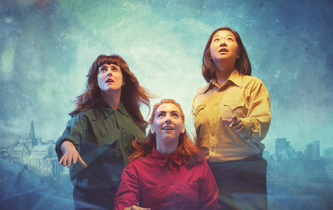 Three females looking up in amazement against a night-time skyline of a city