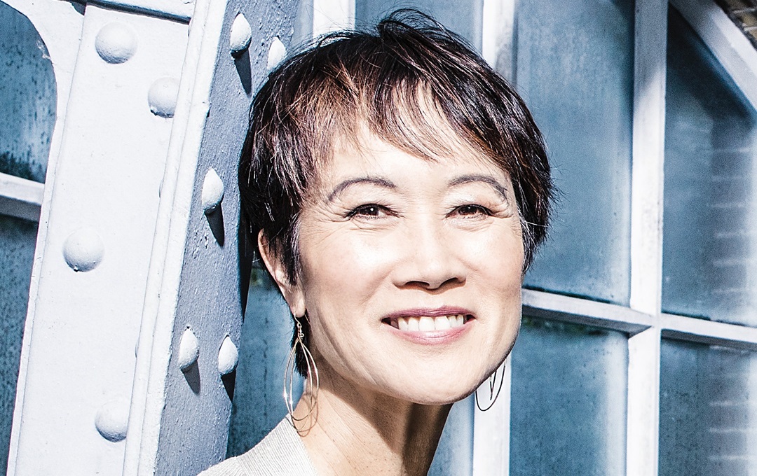 Tess Gerritsen smiling at the camera infront of a steel framed window
