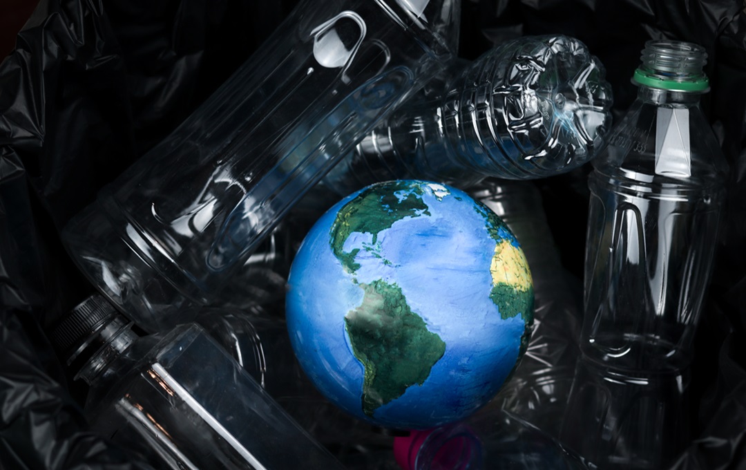 An Earth globe lying amongst discarded plastic bottles
