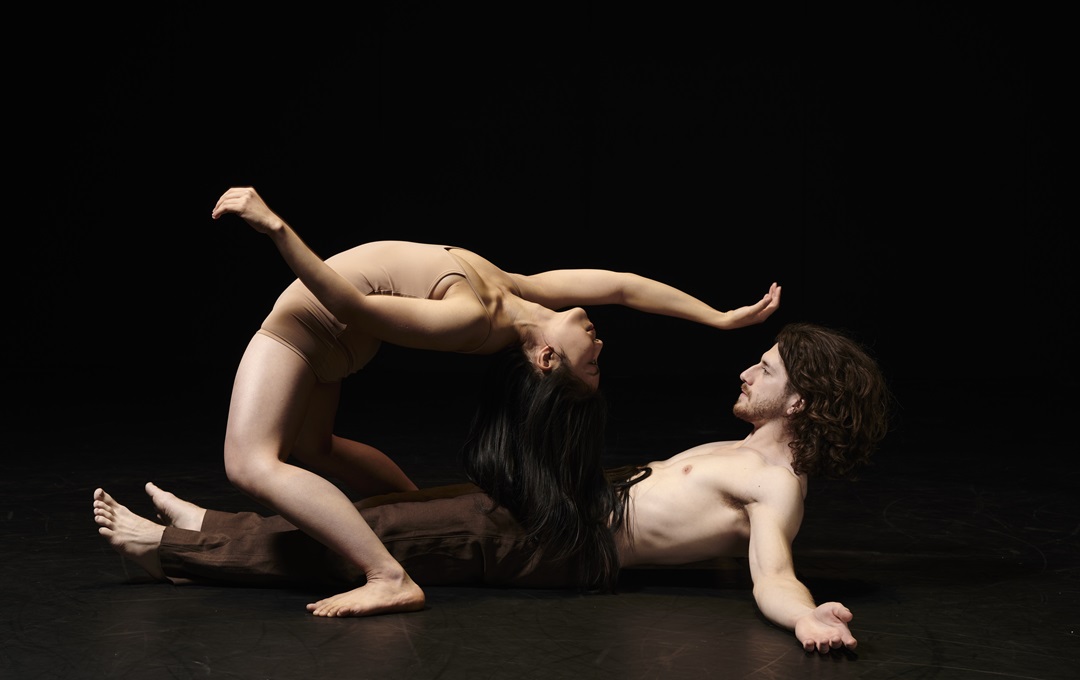Two dancers performing against a black background