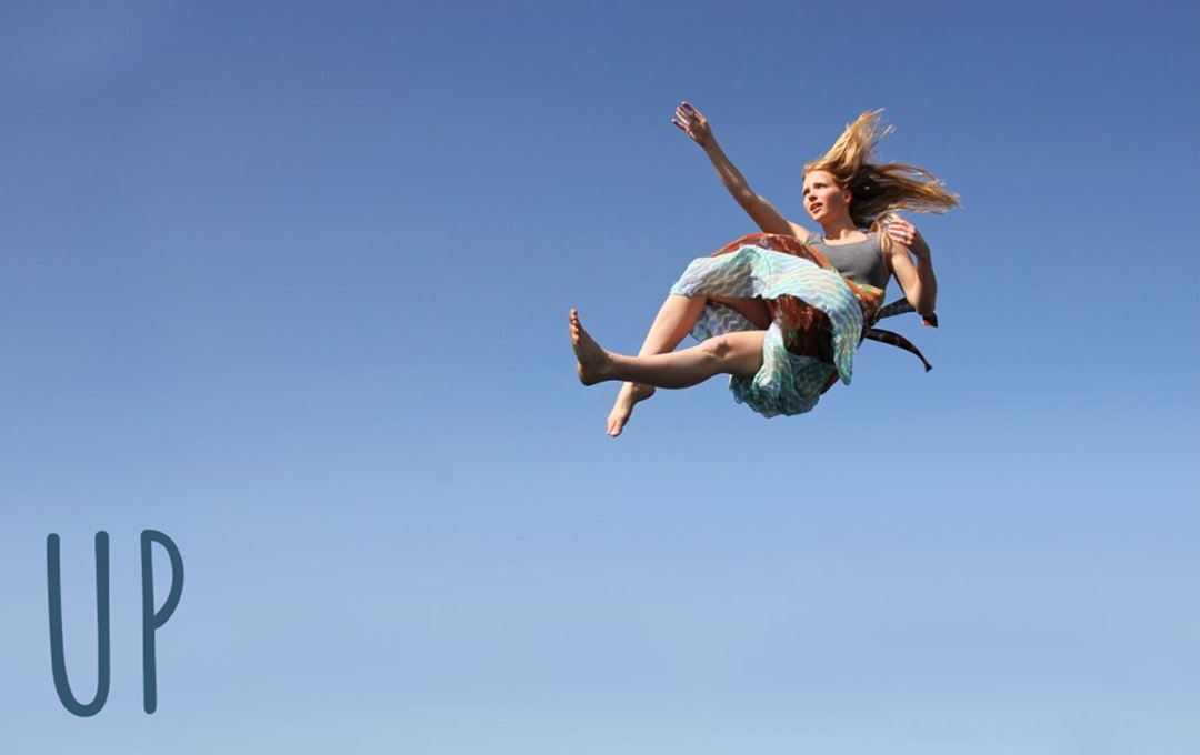 A photo of a girl in mid air against a blue sky.